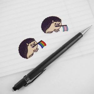 mini stickers of hedgehogs holding pride flags in their mouths. Illustrated.